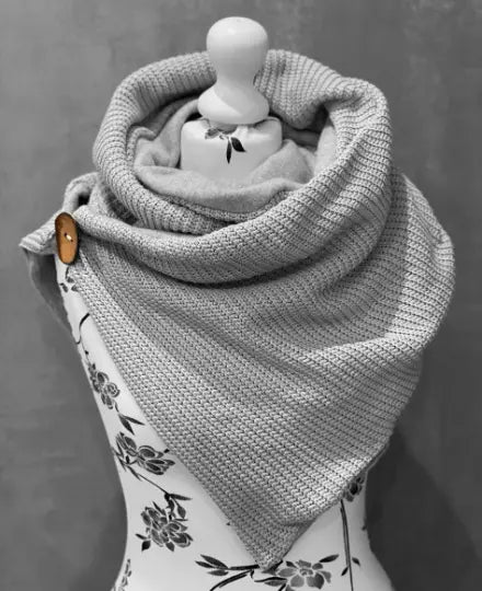 Hellgrauer Wickelschal in Dreiecksform, aus gestricktem Material, zeigt die einfache, elegante Gestaltung.