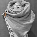 Hellgrauer Wickelschal in Dreiecksform, aus gestricktem Material, zeigt die einfache, elegante Gestaltung.