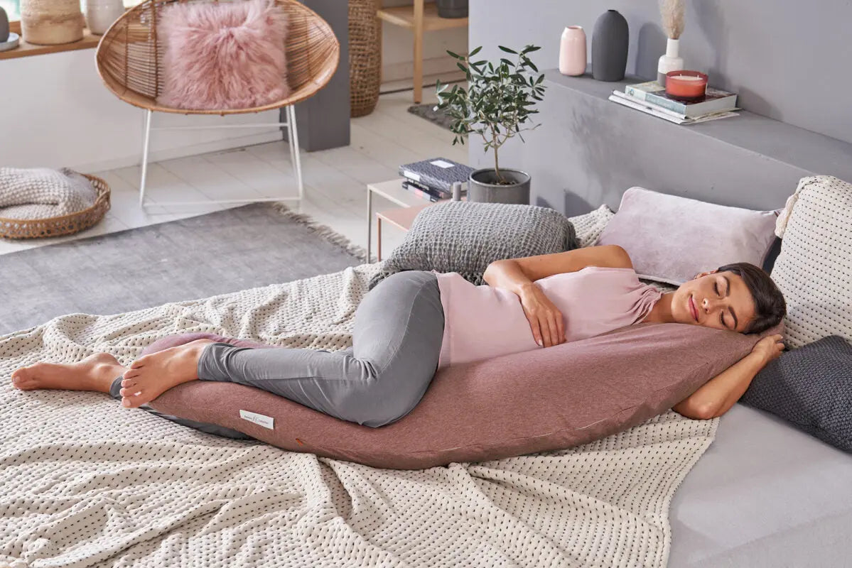 Theraline Stillkissen mit individuellem Bezug, schwangerer Frau liegt bequem auf dem Kissen, personalisierte Stickerei sichtbar