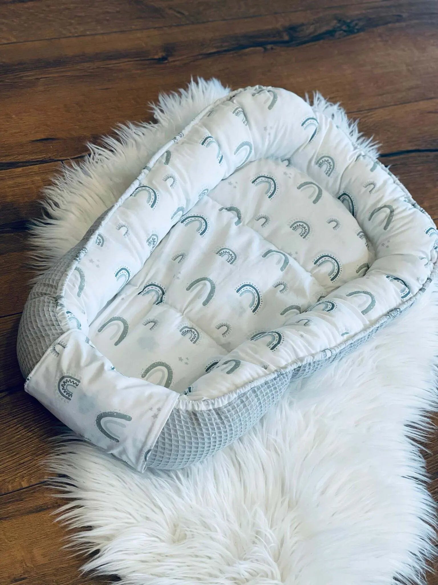Weiches Babynestchen von Mein Shop mit individuell konfigurierbarem Schutz für sicheren Babyschlaf, auf dem Bett liegend.