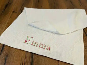 Personalisierte Babydecke aus Waffelstoff mit buntem Namensstickmuster, weiche Textur, für Neugeborene und kleine Babys.